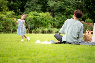 Baba ve kızı parkta pikniğin tadını çıkarıyorlar, neşeli bir açık hava yaşam tarzı yaratıyorlar.