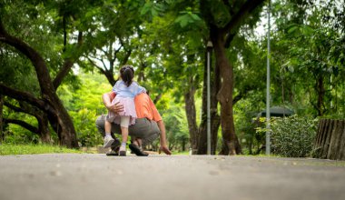 Büyükbaba ve torun parkta birlikte koşuyorlar, sağlıklı yaşam tarzını ve aile bağlarını destekliyorlar.