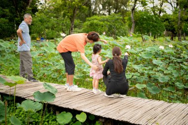 Asyalı bir aile, şehrin ortasında büyük bir çiçek bahçesinde büyük bir çiçek bahçesinde geziniyor.