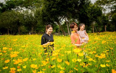 Ebeveynler ve kızları şehrin ortasındaki büyük bir çiçek bahçesinde geziniyorlar.