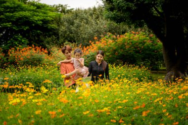 Ebeveynler ve kızları şehrin ortasındaki büyük bir çiçek bahçesinde geziniyorlar.