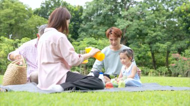 Mutlu Asyalı nesiller parkta pikniğin tadını çıkararak neşeli bir açık hava yaşam tarzı yaratıyor.