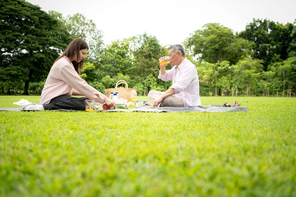 Mutlu Asyalı nesiller parkta pikniğin tadını çıkararak neşeli bir açık hava yaşam tarzı yaratıyor.