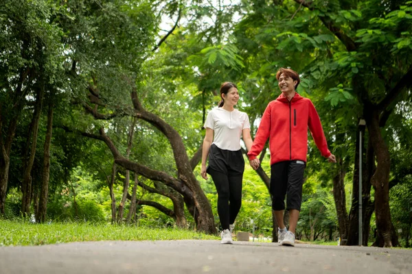 Genç çift parkta birlikte koşuyor, sağlıklı yaşam tarzını ve aile bağlarını destekliyor.