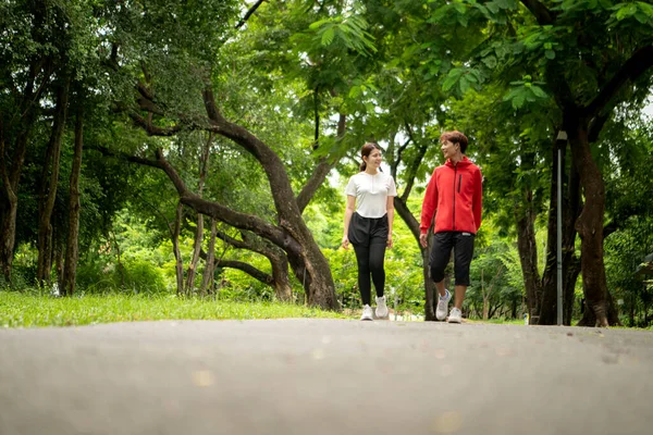 Genç çift parkta birlikte koşuyor, sağlıklı yaşam tarzını ve aile bağlarını destekliyor.