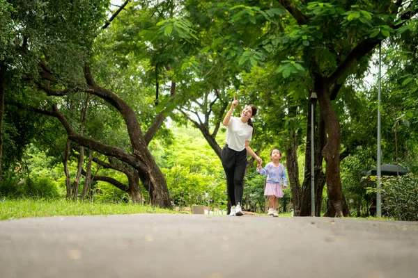 Anne ve kızı parkta birlikte koşuyor, sağlıklı yaşam tarzını ve aile bağlarını destekliyor.