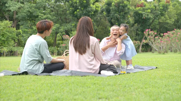 Mutlu Asyalı nesiller parkta pikniğin tadını çıkararak neşeli bir açık hava yaşam tarzı yaratıyor.