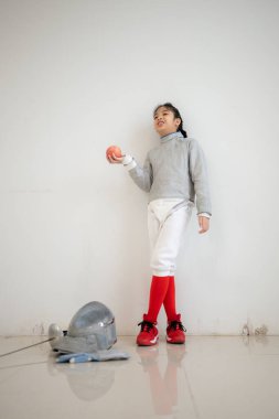 Eskrim kıyafeti giymiş bir kız, yaklaşan yarışma gününe hazırlanmak için meyve ve spor malzemeleri hazırlıyor.