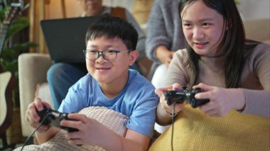 Torunlarıyla rahat bir oturma odasında video oyunu oynayan mutlu büyükanne ve büyükbaba.