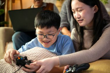 Torunlarıyla rahat bir oturma odasında video oyunu oynayan mutlu büyükanne ve büyükbaba.