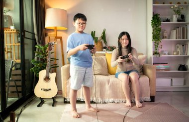 İki mutlu kardeş evlerinin rahat oturma odasında video oyunu oynuyorlar.