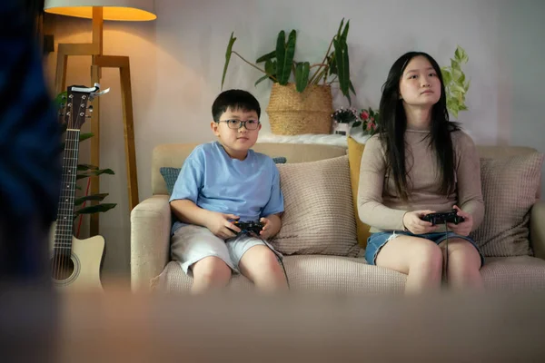 İki mutlu kardeş evlerinin rahat oturma odasında video oyunu oynuyorlar.