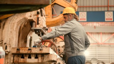 Kıdemli teknisyen metal levha fabrikasında büyük bir makineyi kontrol ediyor.