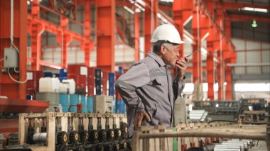 Fabrika makineleri üzerinde çalışırken sırt ağrısı çeken koruyucu ekipmanlı sanayi işçisi.