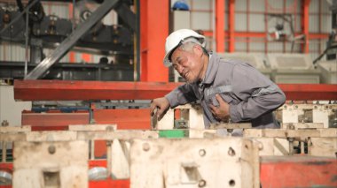 Fabrika makineleri üzerinde çalışırken göğüs ağrısı çeken koruyucu ekipman sanayi işçisi.