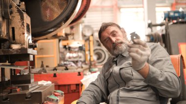 Kıdemli teknisyen metal levha fabrikasında büyük bir makineyi kontrol ediyor.