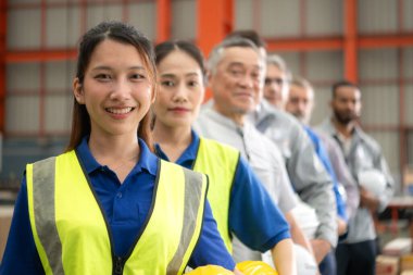 Bir grup endüstriyel işçi güvenlik kaskı takan bir fabrikada büyük bir metal tüpü inceliyor.