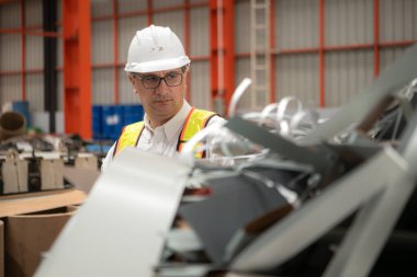 Sanayi işçisi, güvenlik kaskı takan bir fabrikada büyük bir metal tüpün içini inceliyor.
