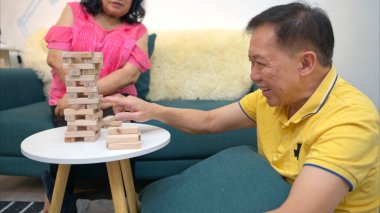 Tatilde, yaşlı bir çift evin oturma odasında Jenga oyunu oynuyor.