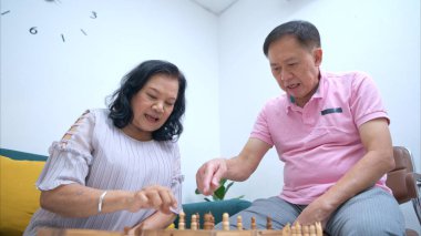 Üst düzey çift evde satranç oynuyor, boş zamanlarının ve zihinsel egzersizlerinin tadını çıkarıyorlar.