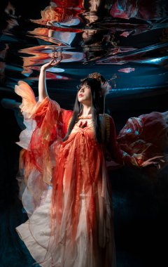 Geleneksel kırmızı kostümlü Asyalı kadın, altın detayları olan, Stüdyoda zarif bir şekilde poz veren,