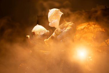 Geleneksel Hanuman maskeleri ve süslü kostümler giyen iki Khon sanatçısı karanlık bir sahnede Tayland Ramayana 'dan dramatik bir sahne sahneleyecekler.
