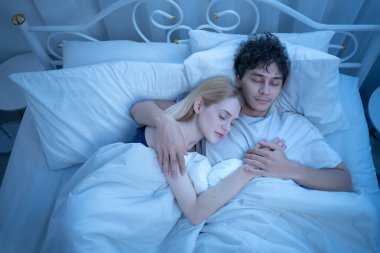 Sevgi dolu bir çift gece yatakta barışçıl bir şekilde sarılıp sıcaklığını, sevgisini ve duygusal bağını belli ediyor.