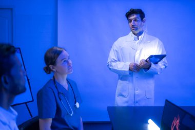 Doktorlar ve tıp uzmanları kalp sağlığını modern hastane ortamında fütürist hologram teknolojisiyle tartışıyor.