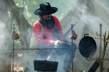 Kamp ateşinde yemek hazırlayan kovboylar, sıcak ve kırsal alanda birlikte et kızartıyorlar.