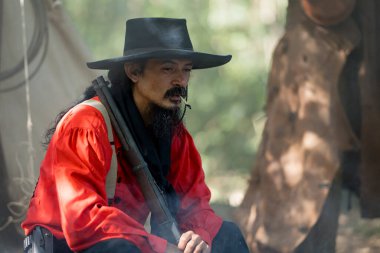 Kamp ateşinde yemek hazırlayan kovboylar, sıcak ve kırsal alanda birlikte et kızartıyorlar.