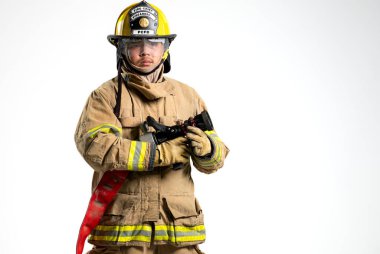 İtfaiye ve yangın hortumu tutan koruyucu üniformalı bir itfaiyecinin portresi. Bireyler, beyaz bir arka plana karşı güvenle dururlar.