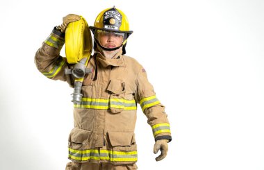 İtfaiye hortumu ve yangın hortumu tutan koruyucu üniformalı bir itfaiyecinin tüm vücut portresi. Bireyler, beyaz bir arka plana karşı güvenle dururlar.