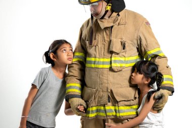 Bir stüdyo fotoğrafı, genç bir çocuğu güvenli bir yere götüren tam teçhizatlı bir itfaiyeciyi gösteriyor.