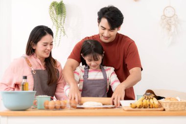 Kızlarının mutfakta hamuru sarmasına yardım eden bir aile, eğlenceli bir pişirme anının tadını çıkarıyor.