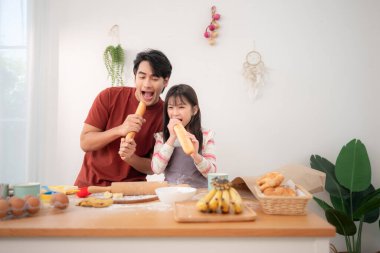 Bir baba ve kız mutfakta ekmek yiyormuş gibi yaparak eğlenceli ve neşeli bir aile anı yaratıyor.