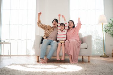 Bir aile birlikte kanepede oturuyor, televizyon izliyor ve parlak bir oturma odasında patlamış mısırın tadını çıkarıyor.