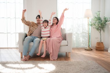 Bir aile birlikte kanepede oturuyor, televizyon izliyor ve parlak bir oturma odasında patlamış mısırın tadını çıkarıyor.