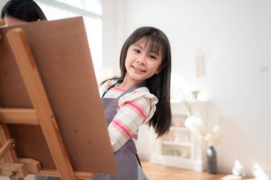 Evde bir oturma odasında odaklanmış ve yaratıcılıkla resim yapan küçük bir kız.