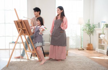 Ebeveynler kızlarına sehpada resim yaparken rehberlik ederler. Birlikte yaratıcı bir aile aktivitesinin tadını çıkarırlar.