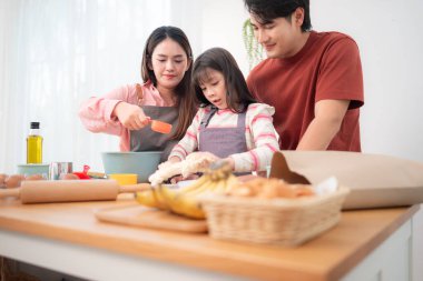 Kızlarının mutfakta hamuru sarmasına yardım eden bir aile, eğlenceli bir pişirme anının tadını çıkarıyor.