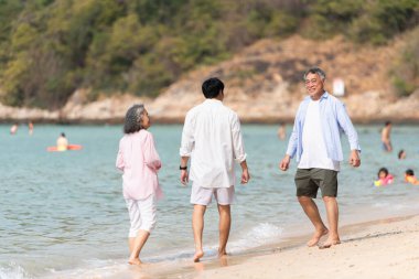 Tatilde, kıyı şeridi boyunca oğluyla yürüyen kıdemli çift gün içinde sahilde konuşurken...
