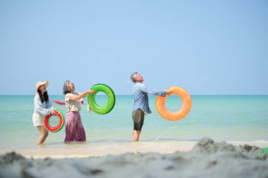 Tatilde, aile fertleri sığ deniz suyunda durur ve gündüz vakti kumsalda birbirlerine şişme yüzükler dağıtırlar.