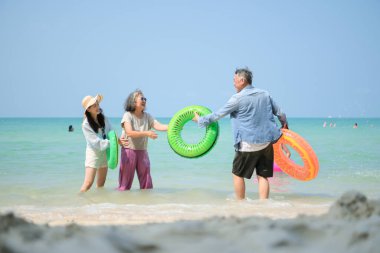 Tatilde, aile fertleri sığ deniz suyunda durur ve gündüz vakti kumsalda birbirlerine şişme yüzükler dağıtırlar.