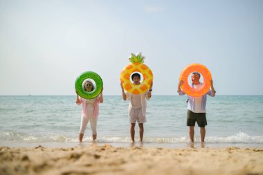 Tatilde, aile üyeleri gün içinde deniz kenarında dururken havaya şişirilebilir yüzükler fırlatıp zıplıyorlar.