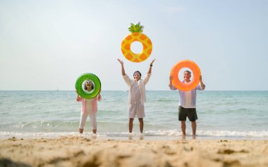 Tatilde, aile üyeleri gün içinde deniz kenarında dururken havaya şişirilebilir yüzükler fırlatıp zıplıyorlar.