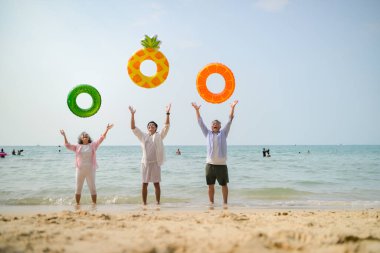 Tatilde, aile üyeleri gün içinde deniz kenarında dururken havaya şişirilebilir yüzükler fırlatıp zıplıyorlar.