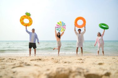 Tatilde, aile üyeleri gün içinde deniz kenarında dururken havaya şişirilebilir yüzükler fırlatıp zıplıyorlar.