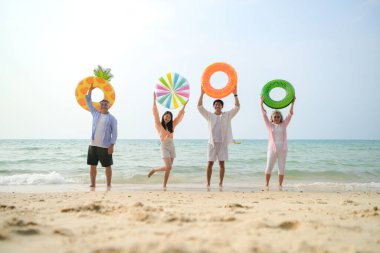 Tatilde, aile üyeleri gün içinde deniz kenarında dururken havaya şişirilebilir yüzükler fırlatıp zıplıyorlar.
