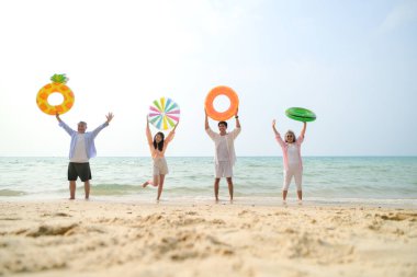 Tatilde, aile üyeleri gün içinde deniz kenarında dururken havaya şişirilebilir yüzükler fırlatıp zıplıyorlar.