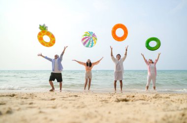 Tatilde, aile üyeleri gün içinde deniz kenarında dururken havaya şişirilebilir yüzükler fırlatıp zıplıyorlar.